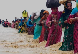 residents evacuate from a flooded area caused by heavy rains, in Balochistan's Lasbela district