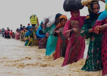 residents evacuate from a flooded area caused by heavy rains, in Balochistan's Lasbela district