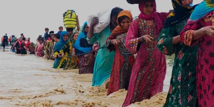 residents evacuate from a flooded area caused by heavy rains, in Balochistan's Lasbela district