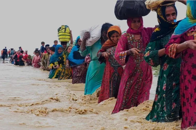 residents evacuate from a flooded area caused by heavy rains, in Balochistan's Lasbela district