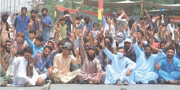 QUETTA: Baloch Yakjehti Committee supporters stage a sit-in on Sariab Road, in front of the Balochistan University, on Wednesday.—Adnan Ahmed